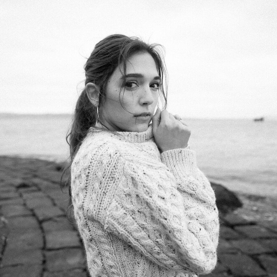 Black and white portrait of Caroline in a cable knit sweater by the water